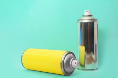 Photo of Cans of different spray paints on color background. Space for text