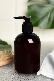 Shampoo bottle, hair brush, towel and green leaf on light table