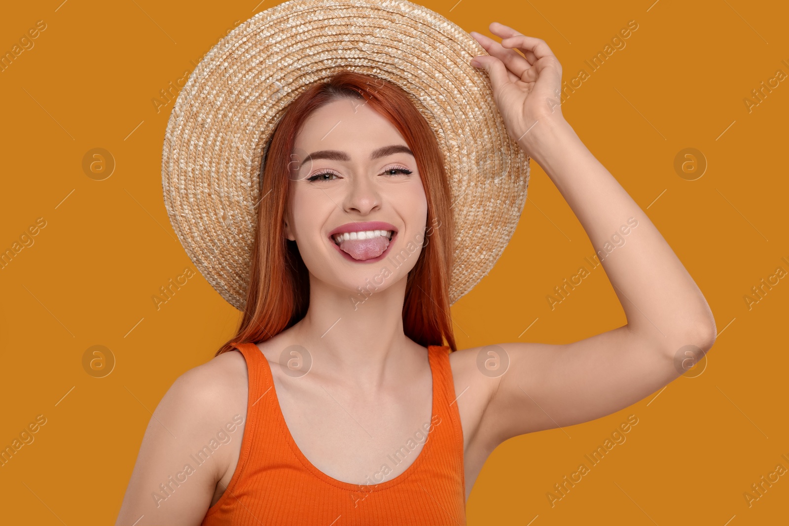 Photo of Happy woman showing her tongue on orange background
