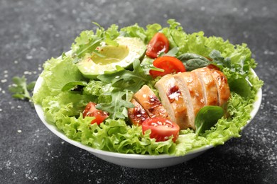 Delicious salad with chicken, cherry tomato and avocado on grey textured table, closeup