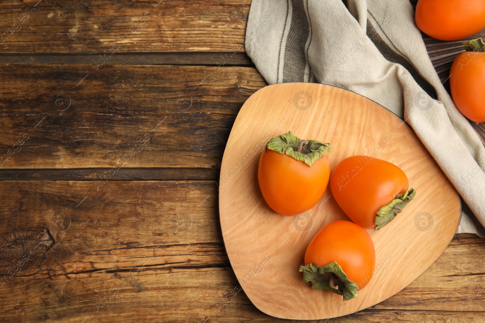 Photo of Tasty ripe persimmons on wooden table, flat lay. Space for text