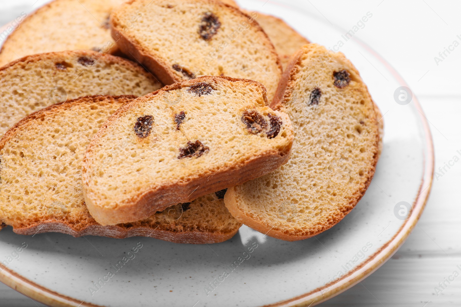 Photo of Plate of sweet hard chuck crackers with raisins on white wooden table