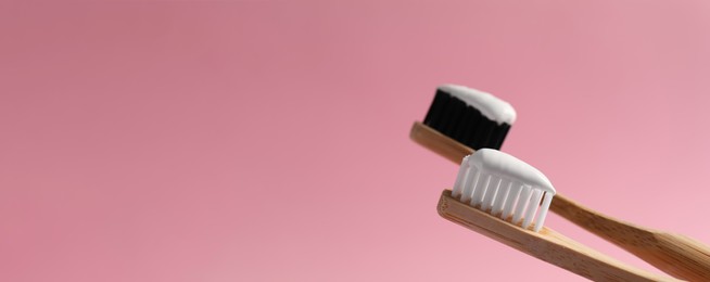 Image of Brushes with toothpastes on pink background, space for text. Banner design