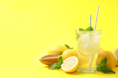 Photo of Natural freshly made lemonade with squeezer on yellow background, space for text. Summer refreshing drink