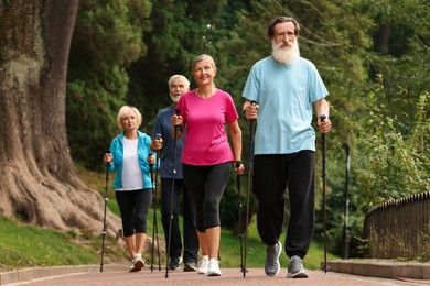 Photo of Group of senior people performing Nordic walking outdoors. Low angle view