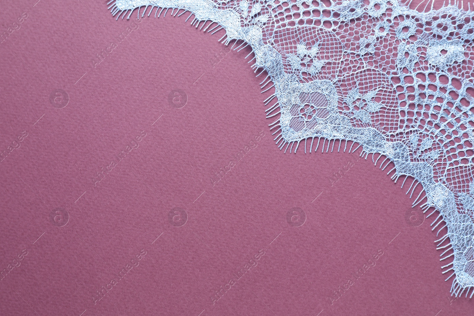 Photo of White lace on purple background, top view. Space for text