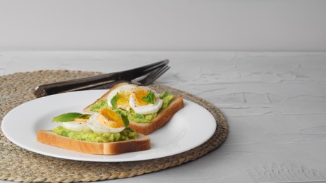 Photo of Tasty sandwiches with boiled egg, avocado and spinach served on white textured table, space for text