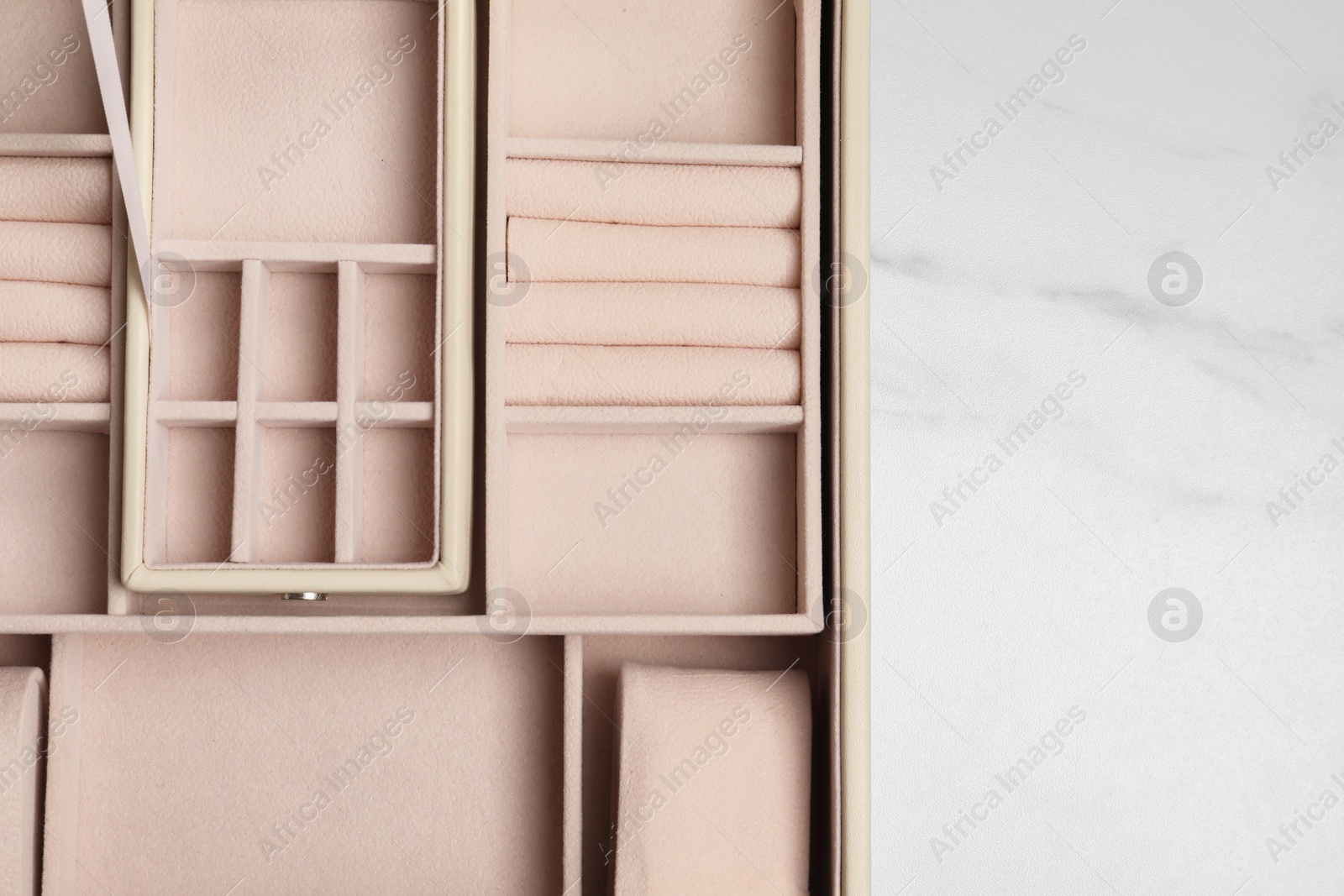 Photo of Empty beige jewelry box on white marble table, top view. Space for text