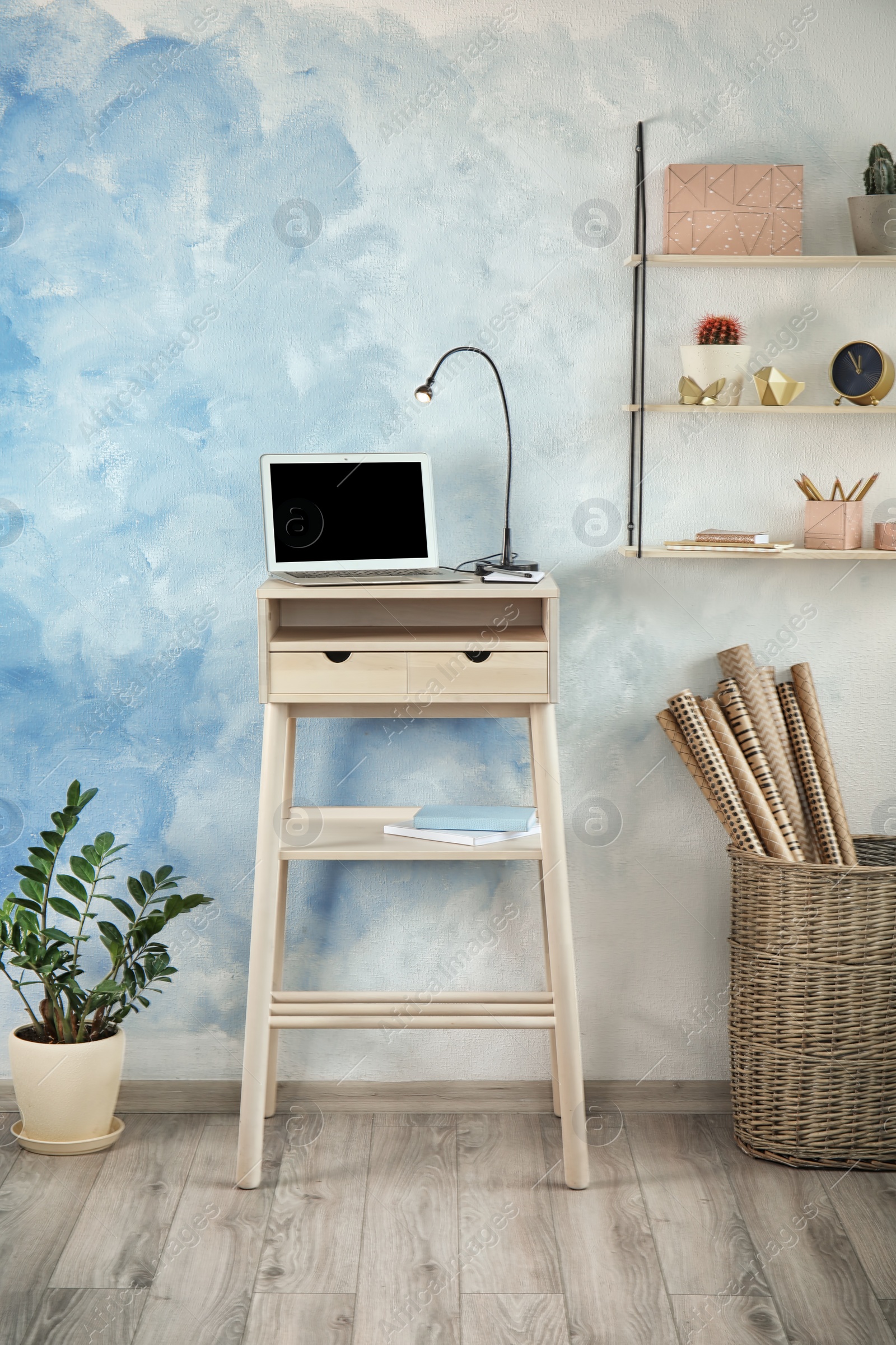 Photo of High wooden table with laptop as stand up workplace in modern interior