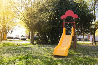 Yellow children's slide and beautiful flowers in park on sunny day