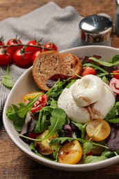 Photo of Delicious burrata salad with colorful cherry tomatoes, croutons and arugula on wooden table, closeup