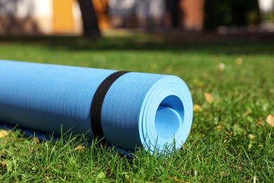 Photo of Blue karemat or fitness mat on fresh green grass in park, closeup