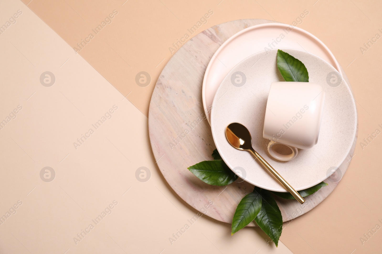Photo of Beautiful table setting with green leaves on beige background, flat lay. Space for text