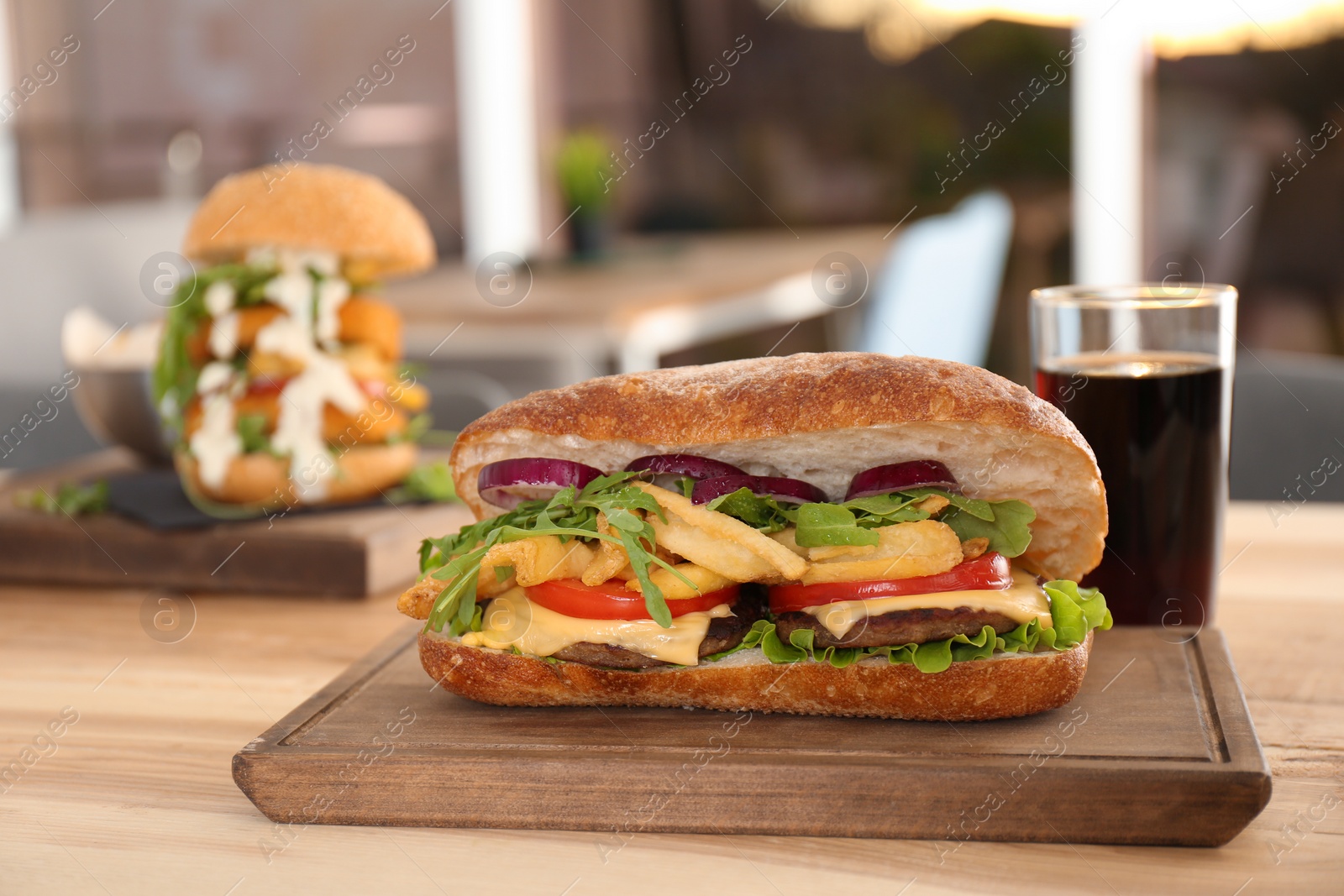 Photo of Wooden serving plate with sandwich on table in cafe