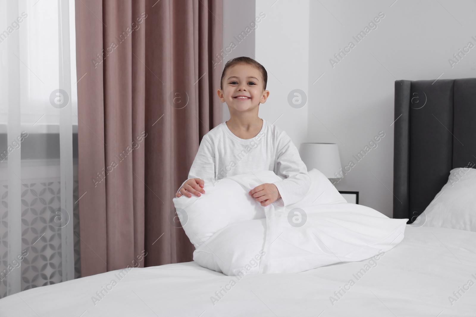 Photo of Cute girl changing pillowcase in bedroom. Domestic chores