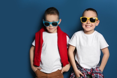 Photo of Portrait of cute twin brothers with sunglasses on color background