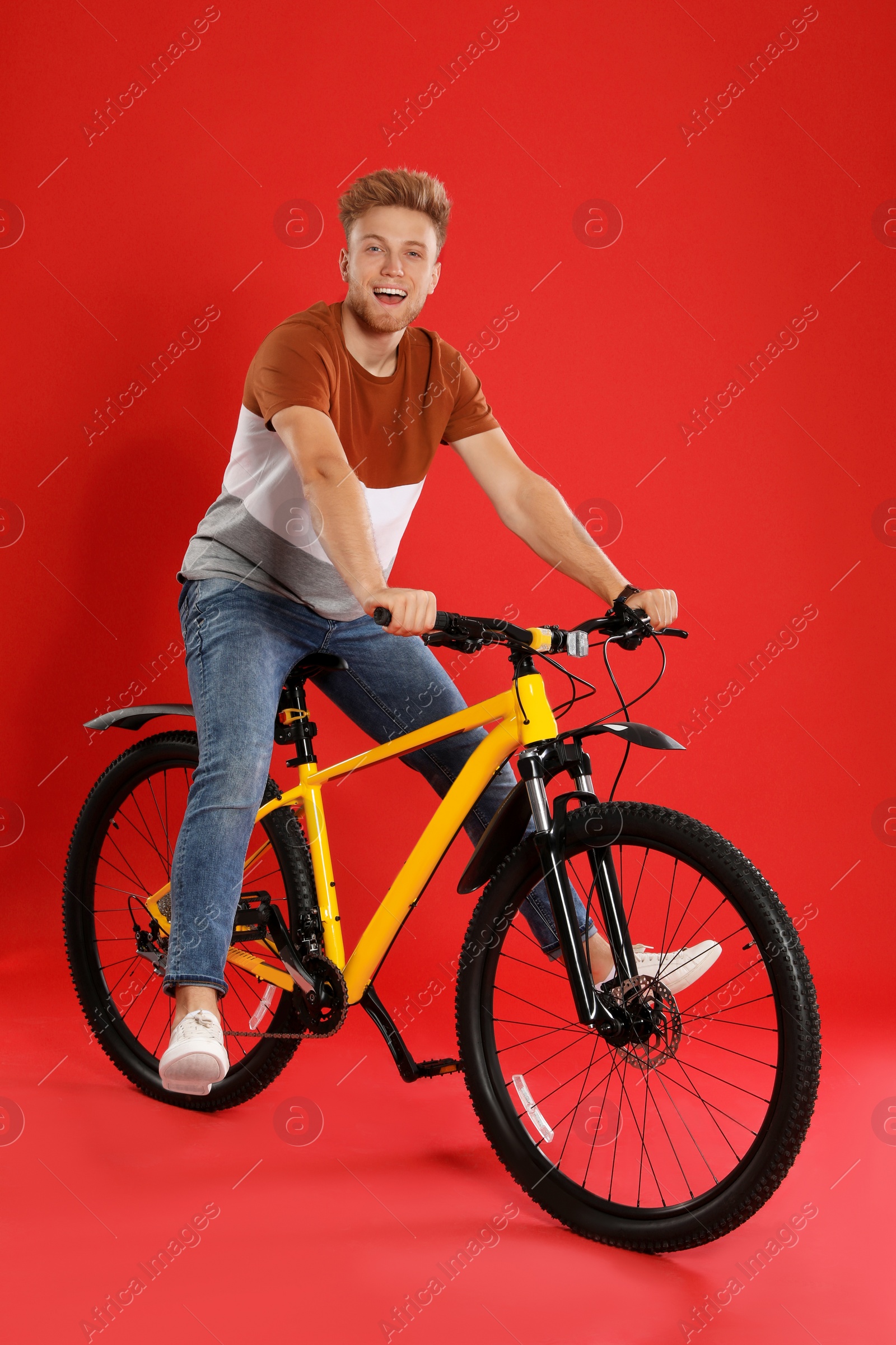Photo of Handsome young man riding bicycle on red background