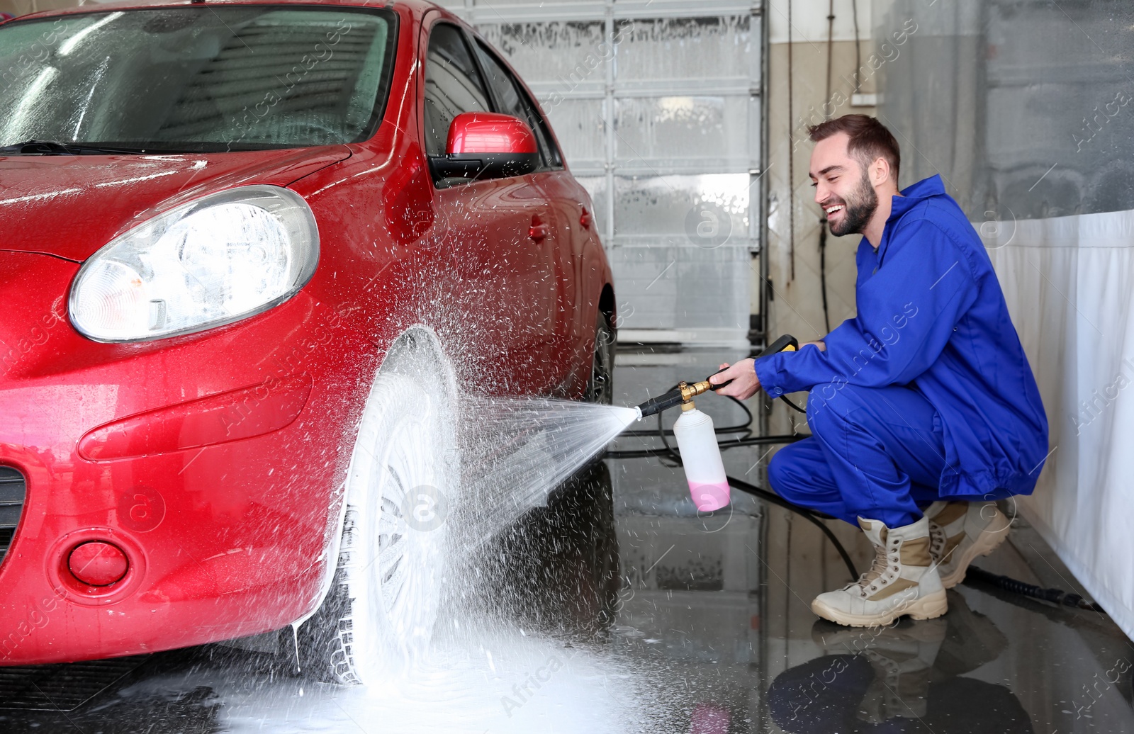 Photo of Worker cleaning automobile with high pressure water jet at car wash