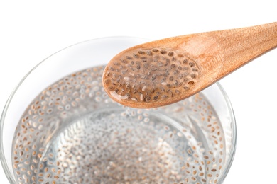 Photo of Spoon with water and chia seeds over glass on white background