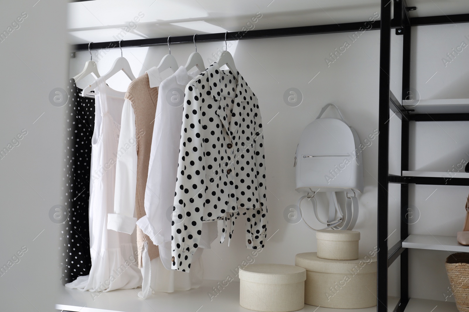 Photo of Storage rack with stylish women's clothes and accessories indoors