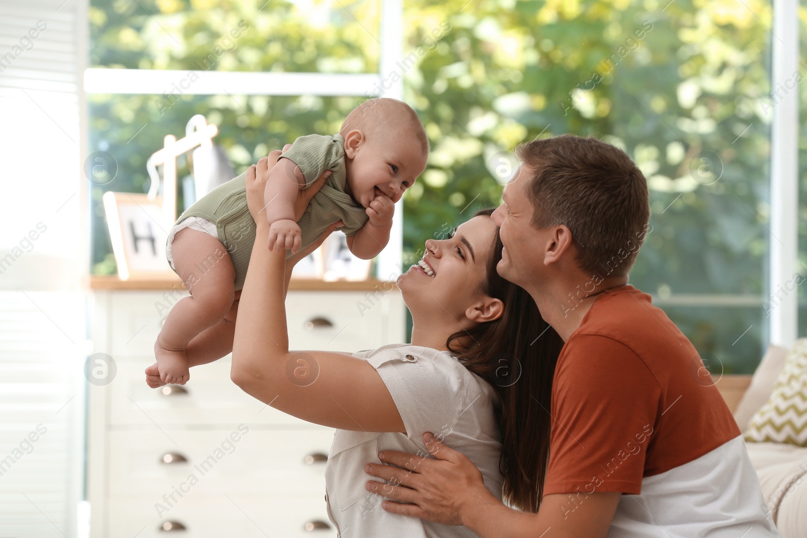 Photo of Portrait of happy family with their cute baby at home