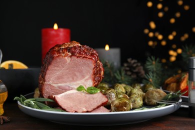 Photo of Delicious ham served with brussels sprouts and rosemary on wooden table against blurred festive lights. Christmas dinner