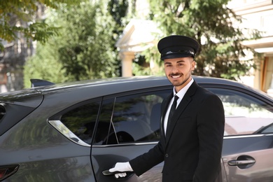 Young handsome driver standing near luxury car. Chauffeur service