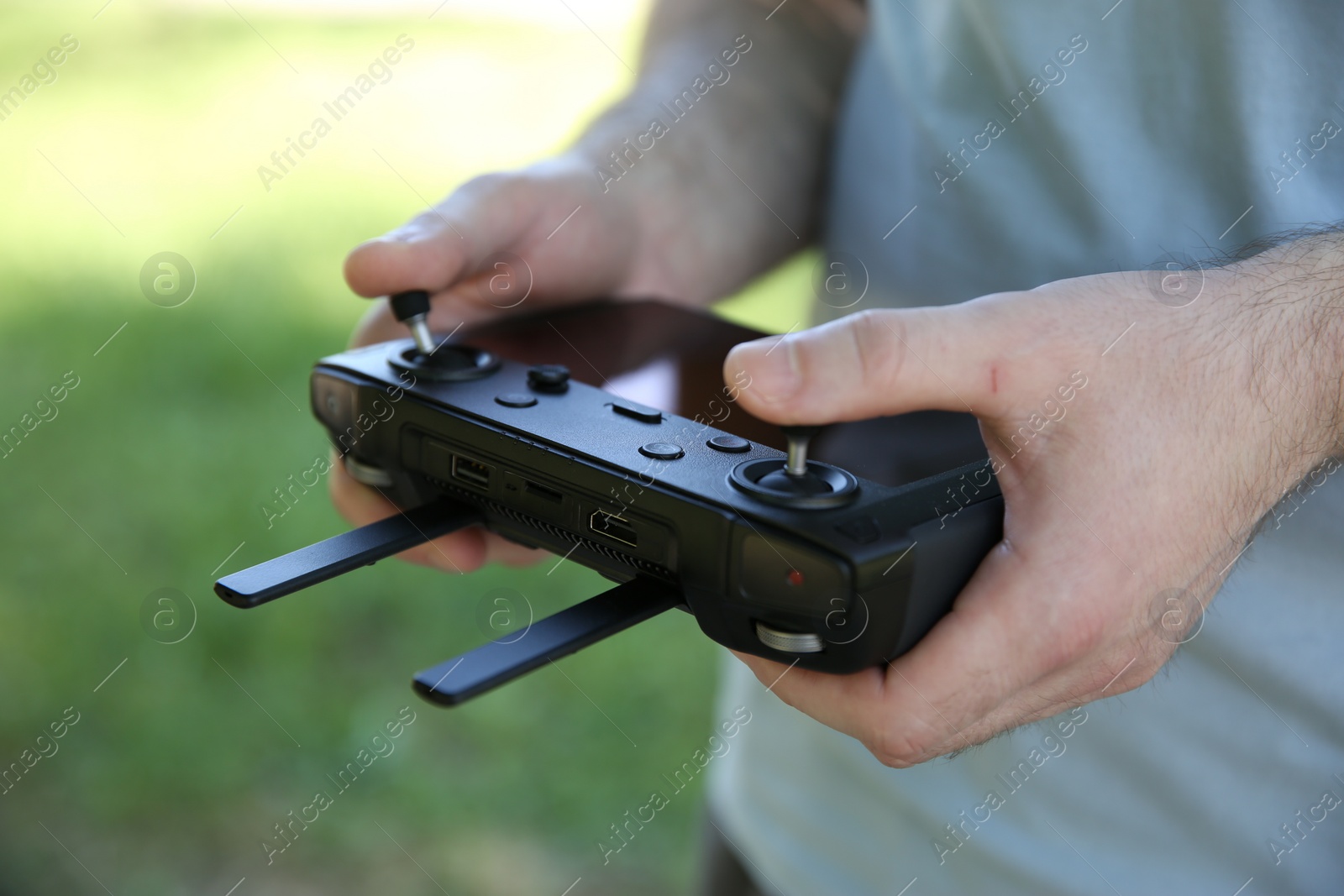 Photo of Man holding new modern drone controller outdoors, closeup of hands