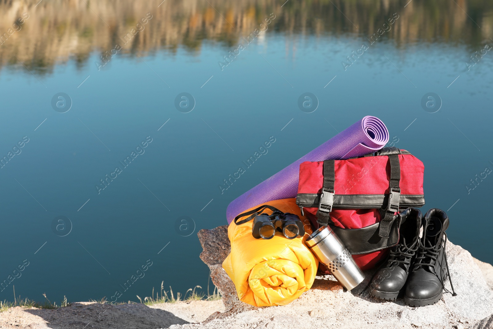 Photo of Set of camping equipment with sleeping bag on ground outdoors. Space for text