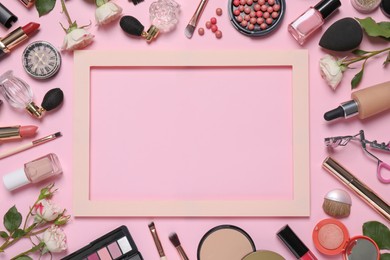 Photo of Flat lay composition with different makeup products and frame on pink background, space for text