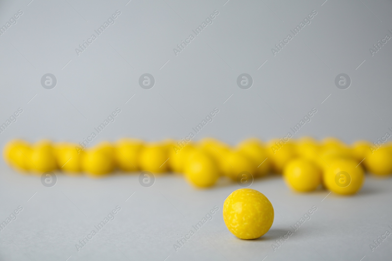 Photo of Delicious lemon chewing gums on light grey background, closeup