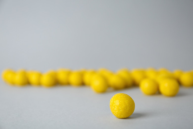 Photo of Delicious lemon chewing gums on light grey background, closeup