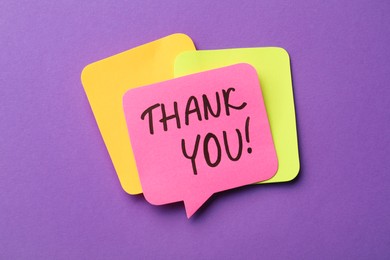 Photo of Pink paper note with phrase Thank You on purple background
