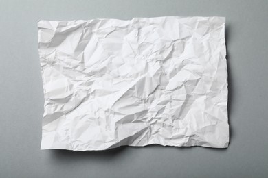 Photo of Sheet of white crumpled paper on grey background, top view