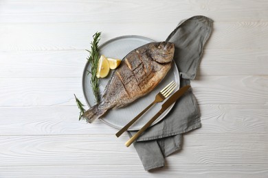Delicious baked fish served with rosemary and lemon on white wooden table, top view. Seafood