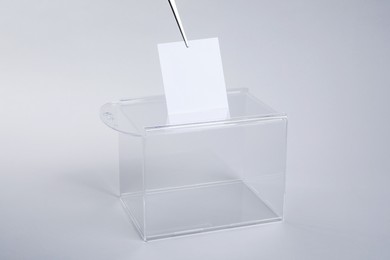 Ballot box with vote on light grey background. Election time