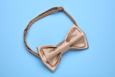 Photo of Stylish beige bow tie on light blue background, top view