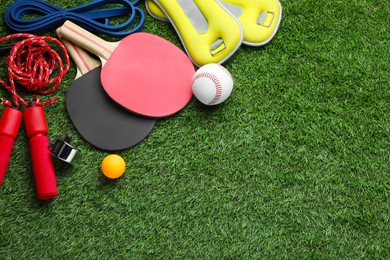 Photo of Set of different colorful sports equipment on green grass, above view. Space for text