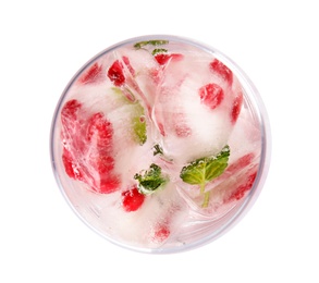 Glass of drink with pomegranate ice cubes on white background, top view