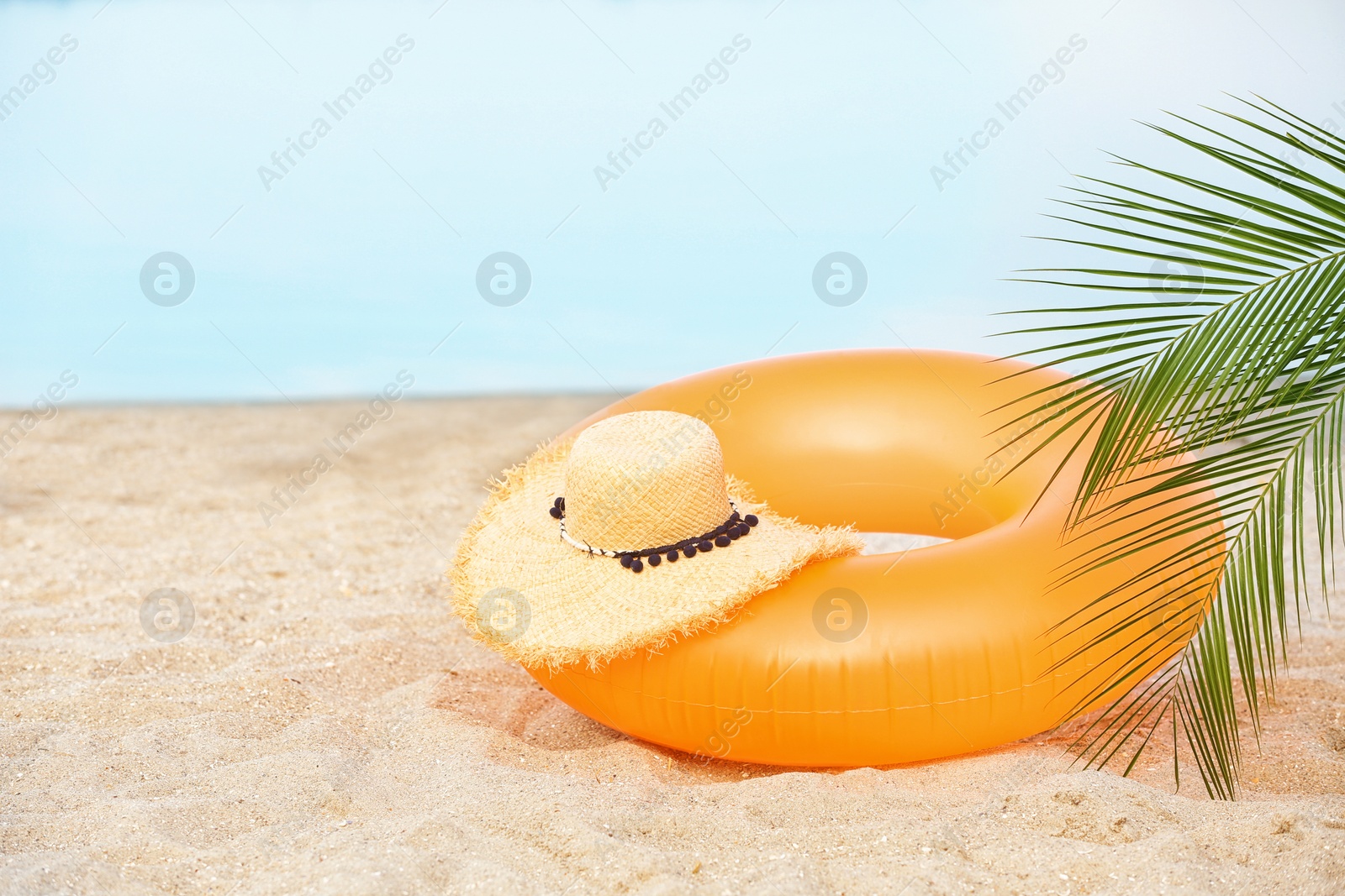 Photo of Colorful inflatable ring and hat on sand. Beach object