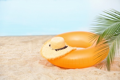 Colorful inflatable ring and hat on sand. Beach object