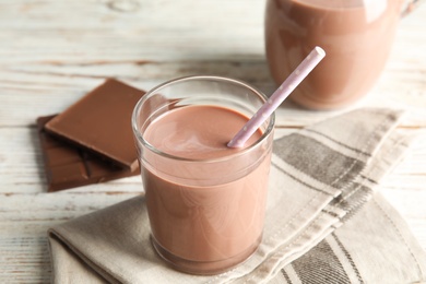 Photo of Glass of tasty chocolate milk on wooden table. Dairy drink