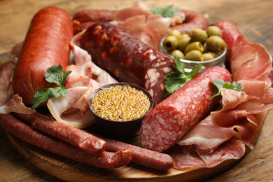 Different types of sausages served on wooden board, closeup