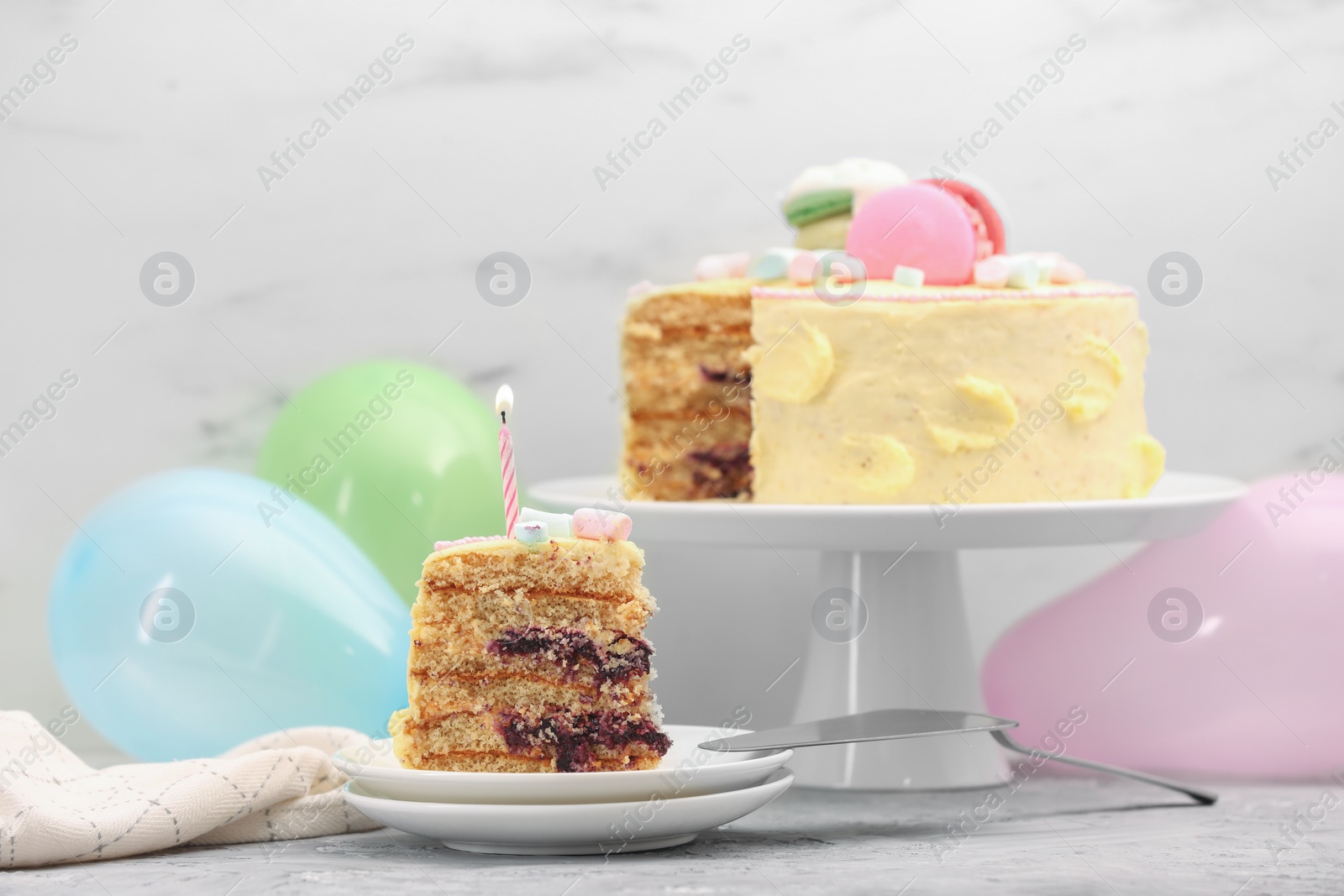 Photo of Piece of delicious cake with burning candle served on light grey table