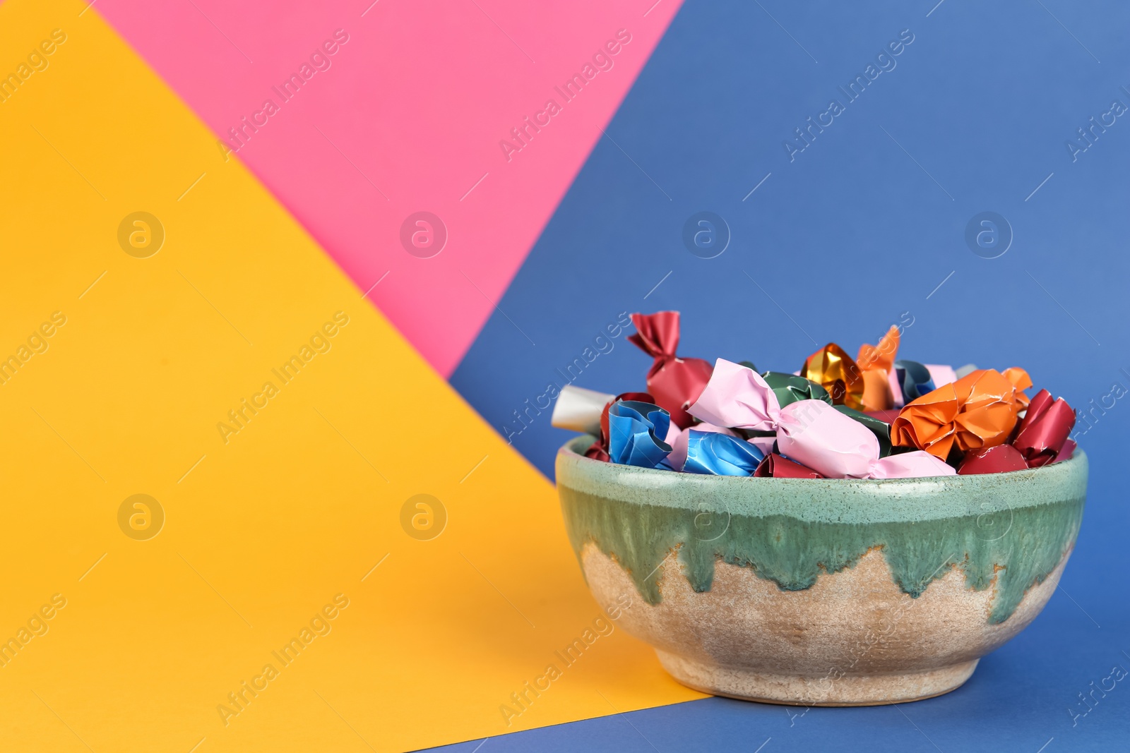 Photo of Candies in different wrappers on color background, space for text