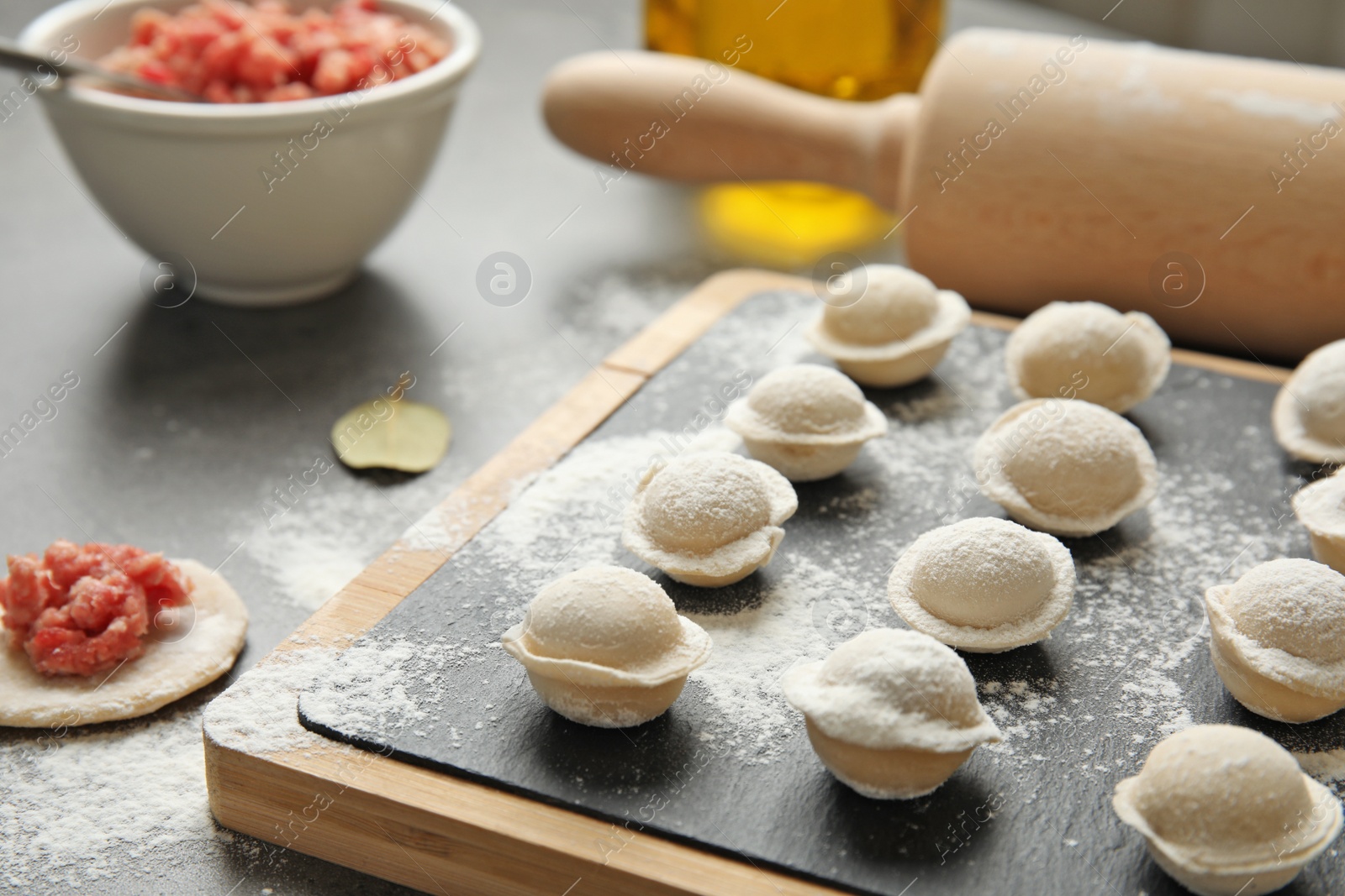 Photo of Board with raw dumplings on table, closeup. Process of cooking