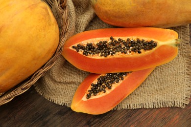 Tasty whole and cut papaya fruits on wooden table, flat lay