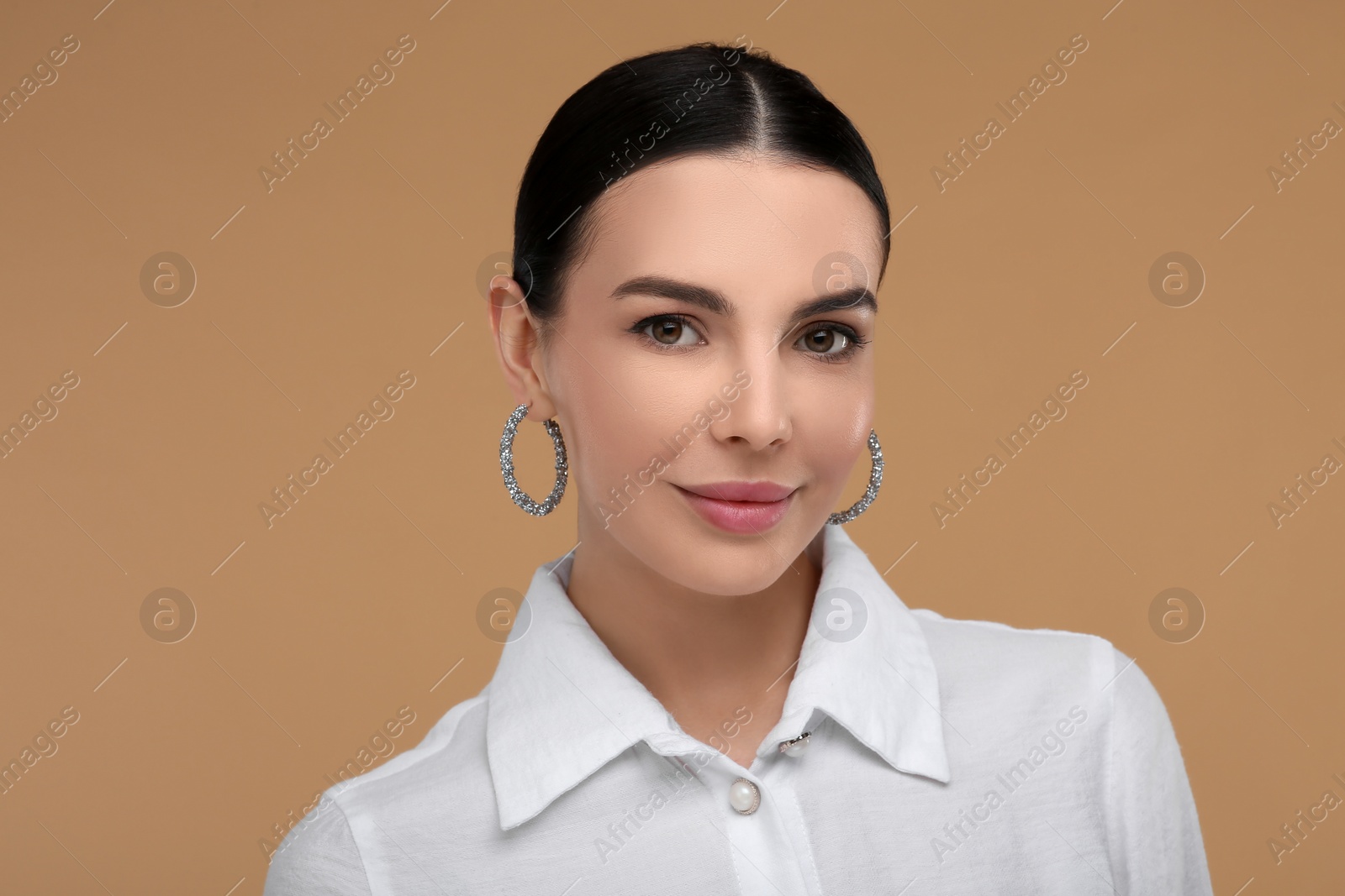 Photo of Beautiful young woman with elegant earrings on beige background