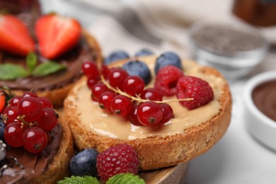 Photo of Tasty organic rusks with different toppings and ingredients on white table, closeup