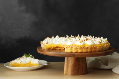 Photo of Stand with delicious lemon meringue pie on wooden table
